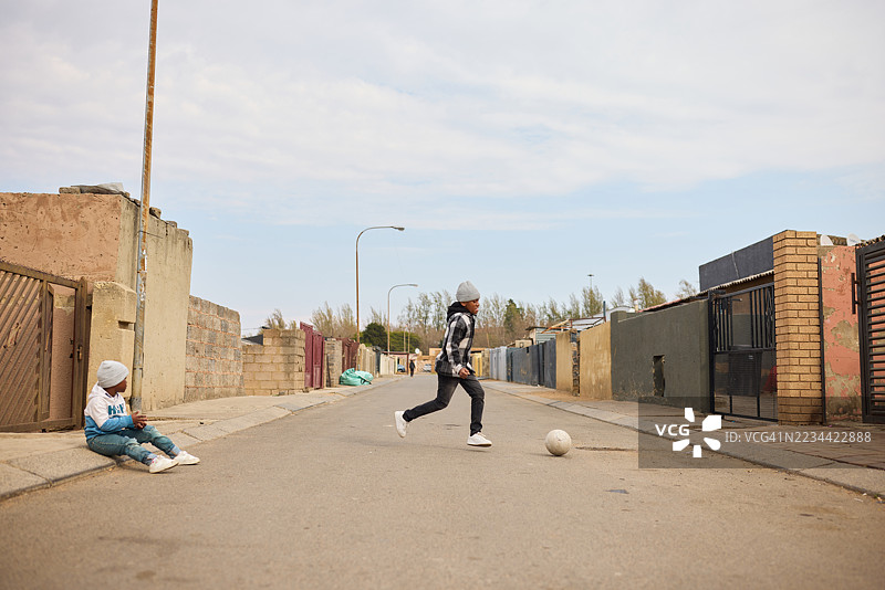 无忧无虑的男孩在奔跑时踢着足球图片素材