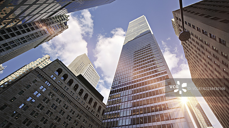 从低角度看阳光照耀的办公摩天大楼，曼哈顿金融区，纽约，美国，背景为纽约联邦储备银行。图片素材