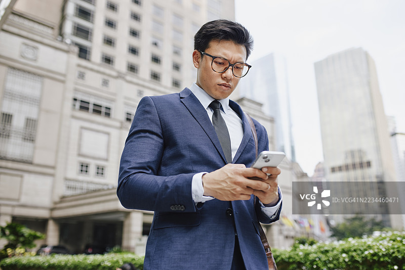 专注的马来西亚亚洲商人在城市中使用智能手机图片素材