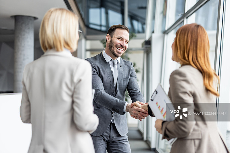 商人在现代办公室与女商人握手图片素材