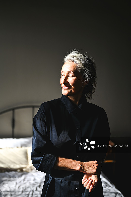 老年女性在卧室放松，享受阳光。图片素材