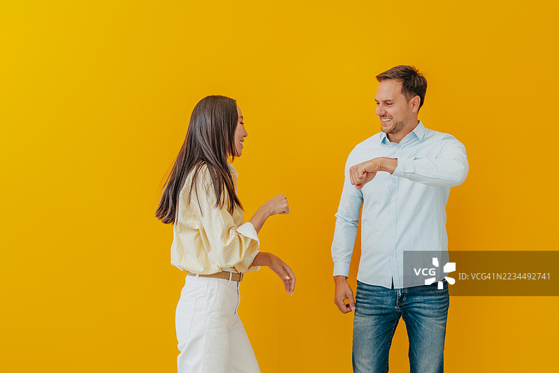 微笑的亚洲女商人与白人男商人在愉快的工作室环境中表达快乐和自信图片素材