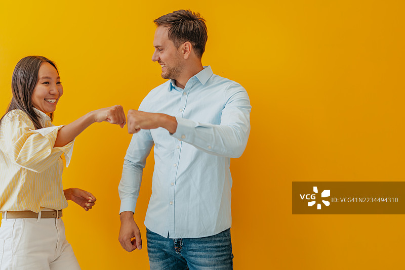 微笑的亚洲女商人与白人男商人在愉快的工作室环境中共同庆祝成功图片素材