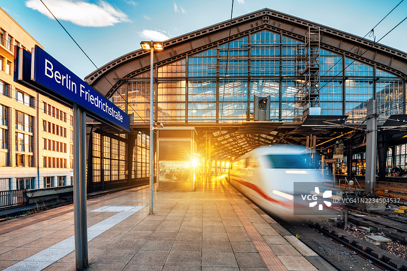 长时间曝光的火车经过柏林弗里德里希大街车站，夕阳逆光下的景象图片素材