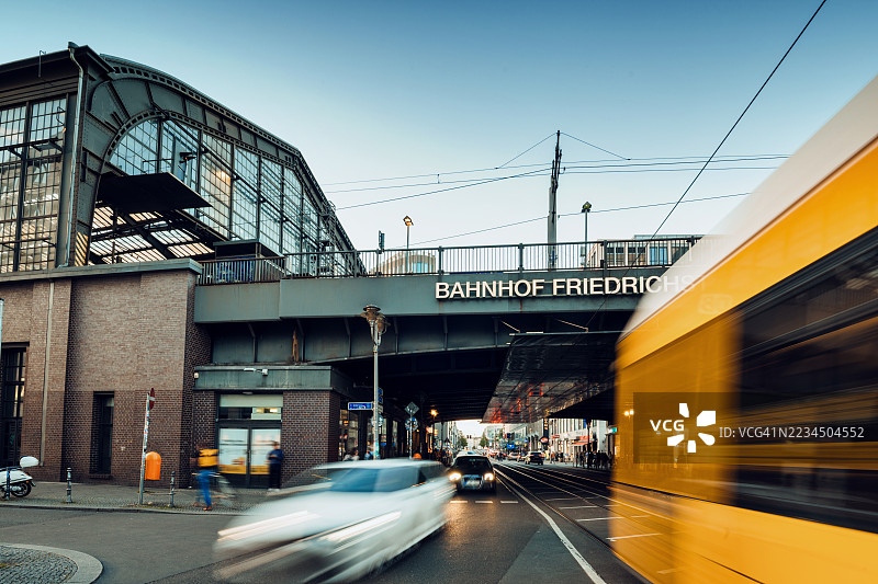 黄昏时分，柏林弗里德里希大街火车站前的黄色电车长时间曝光。图片素材