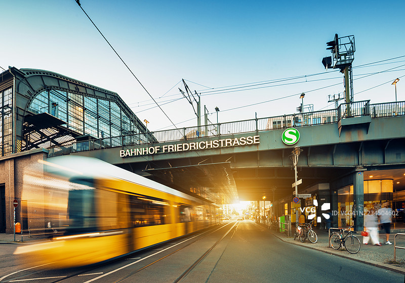 黄昏时分，柏林弗里德里希大街火车站前的黄色电车长时间曝光。图片素材