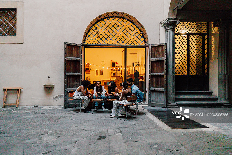 与朋友们在露台上享受披萨切片的休闲晚餐夜图片素材