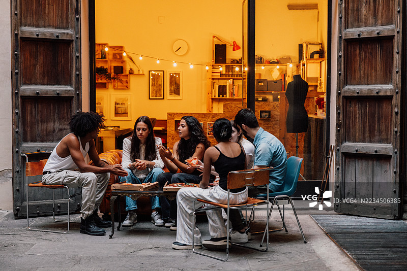 与朋友们在露台上享受披萨片的轻松晚餐夜图片素材