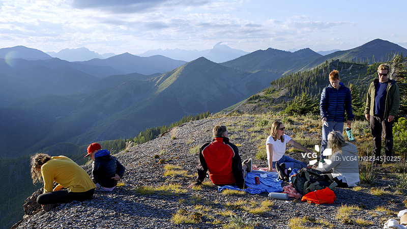 多代家庭在日落时分享受山脊上的野餐图片素材