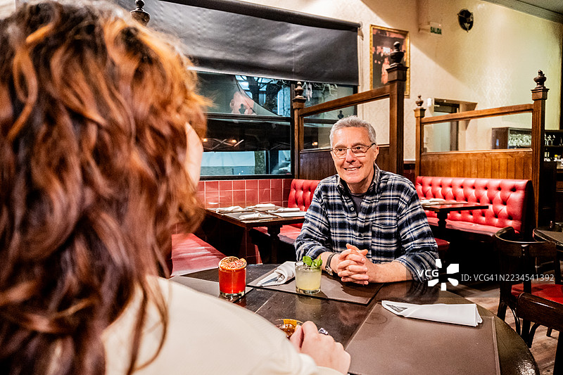 老年男子在酒吧与女儿交谈，喝着鸡尾酒图片素材