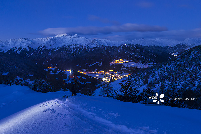 黄昏时分，滑雪登山者在雪景中穿行图片素材