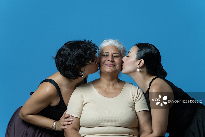 一位年长女性接受两个女儿的亲吻和关爱图片素材