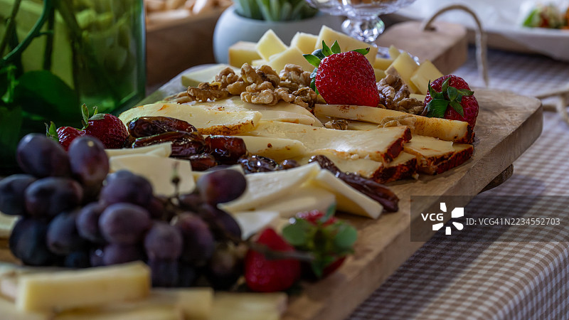 美味的奶酪拼盘，上面摆放着新鲜水果、坚果和枣，适合宴会活动。图片素材