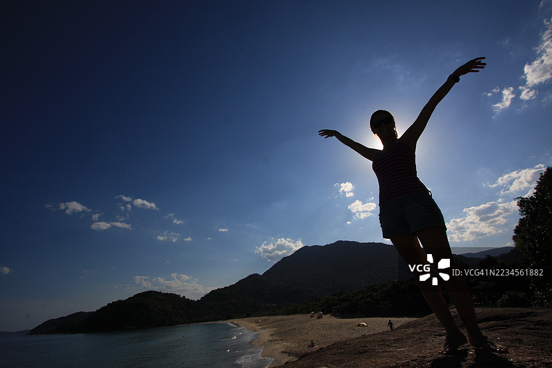 一位女性站在岩石上俯瞰普鲁米林海滩图片素材
