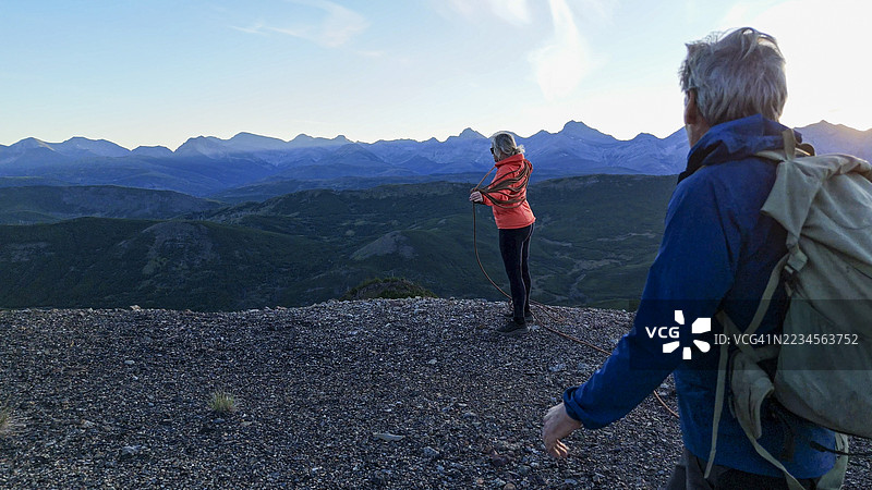 成熟夫妇在日落时分的山顶准备攀岩绳索图片素材