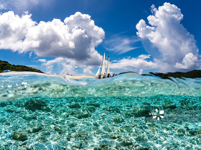 可以看到阳伞、船只,甚至是独特于冲绳的双体船萨巴尼。拍摄了美丽的白沙滩的一半。还有一群热带鱼。美丽的珊瑚礁和游泳的人们。外岛,座间味岛,慶良間群岛。图片素材