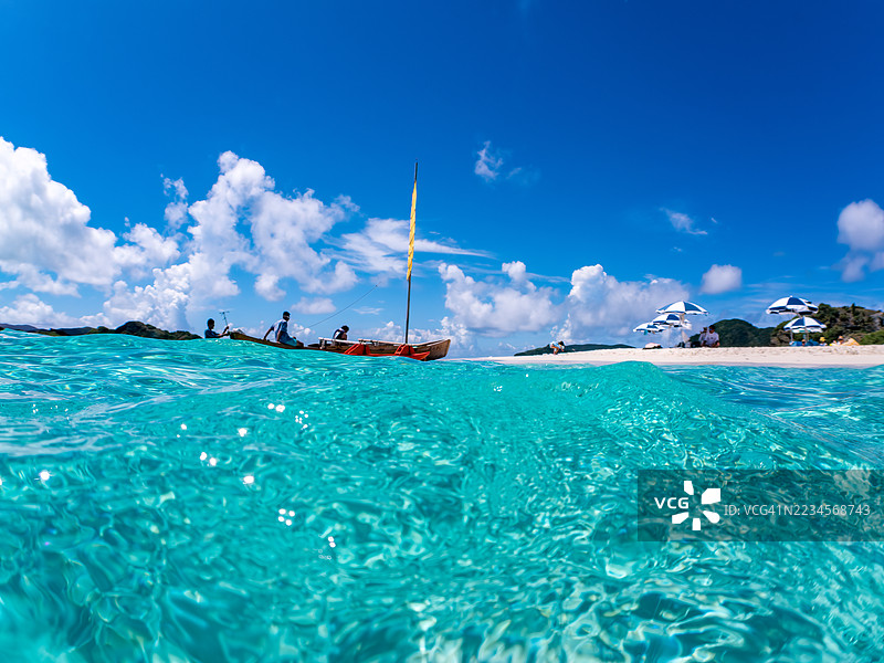 可以看到阳伞、船只,甚至是独特于冲绳的双体船Sabani。拍摄了美丽白沙滩的一半。还有一群热带鱼。美丽的珊瑚礁和游泳的人们。外岛,座间味岛,慶良間群岛。图片素材