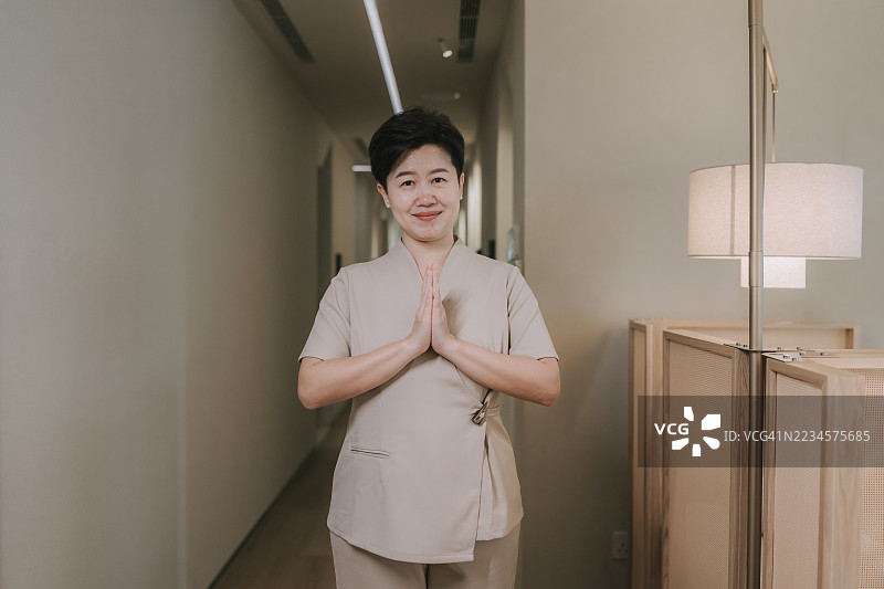 微笑的亚洲水疗师在养生中心用传统的合十礼问候图片素材