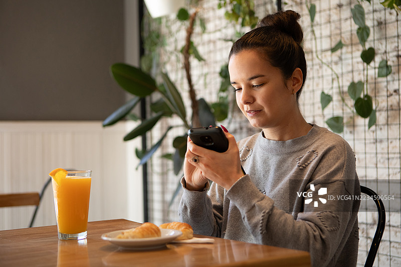 美丽的年轻女性使用带有语音辅助功能的智能手机，帮助视力障碍人士。图片素材