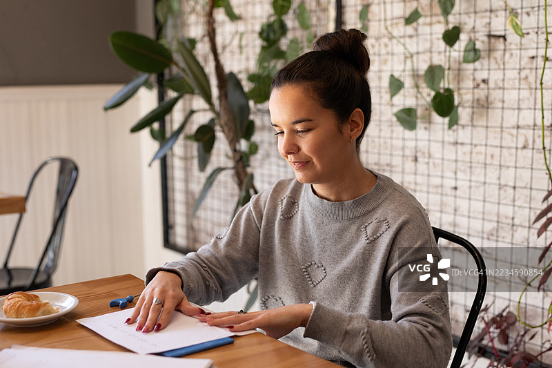 美丽的年轻盲人女性正在使用黑板和模板在纸上写盲文。图片素材