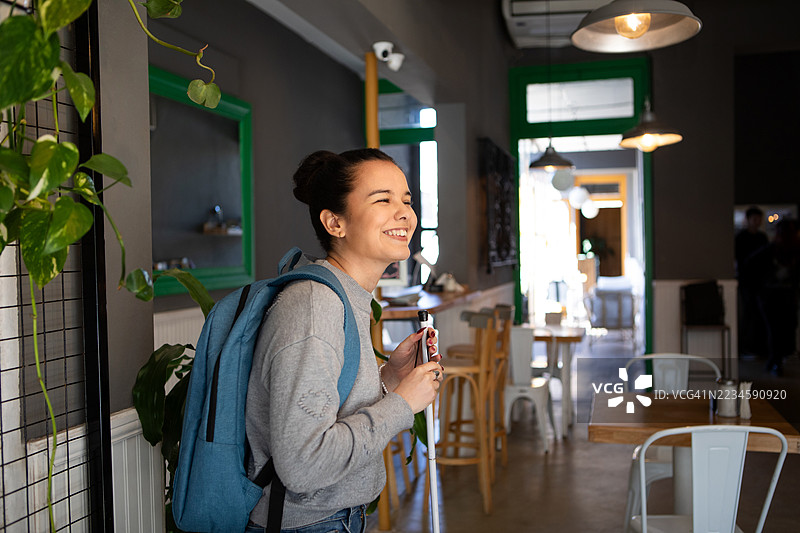 微笑的年轻盲人女性在咖啡馆里用白色手杖行走图片素材