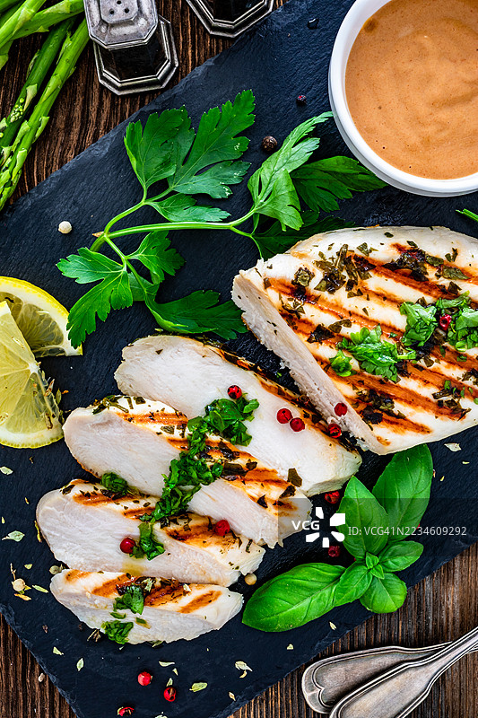 烤鸡胸肉放在黑色石板上，置于木桌上图片素材