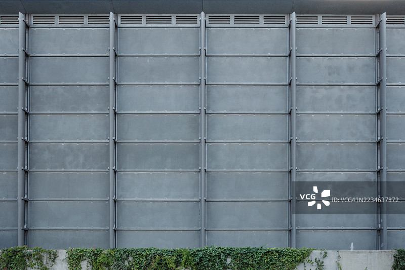 现代工业建筑的对称外立面，配有金属面板和常春藤。图片素材