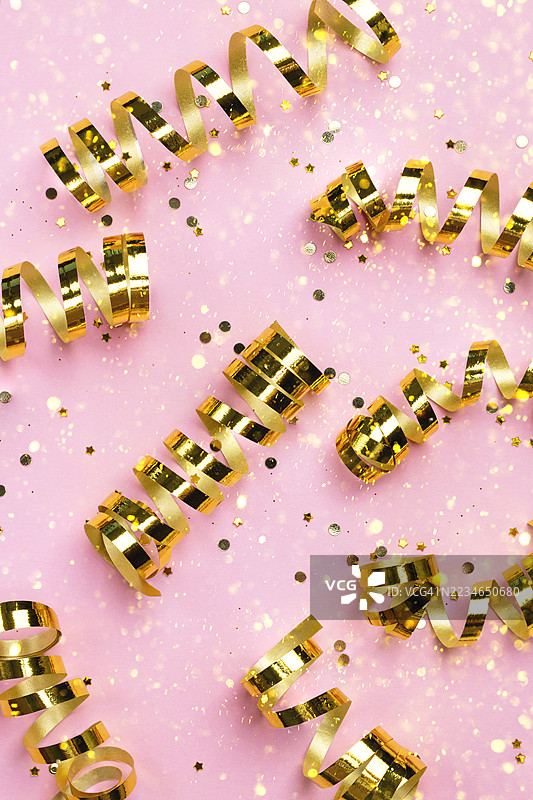 节日背景，配有金色彩带、闪闪发光的亮片和模糊的金色散景灯光图片素材