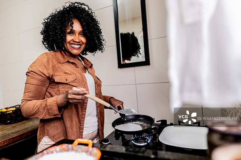 一位成熟的女性在家里的厨房里烹饪巴西木薯薄饼的肖像图片素材