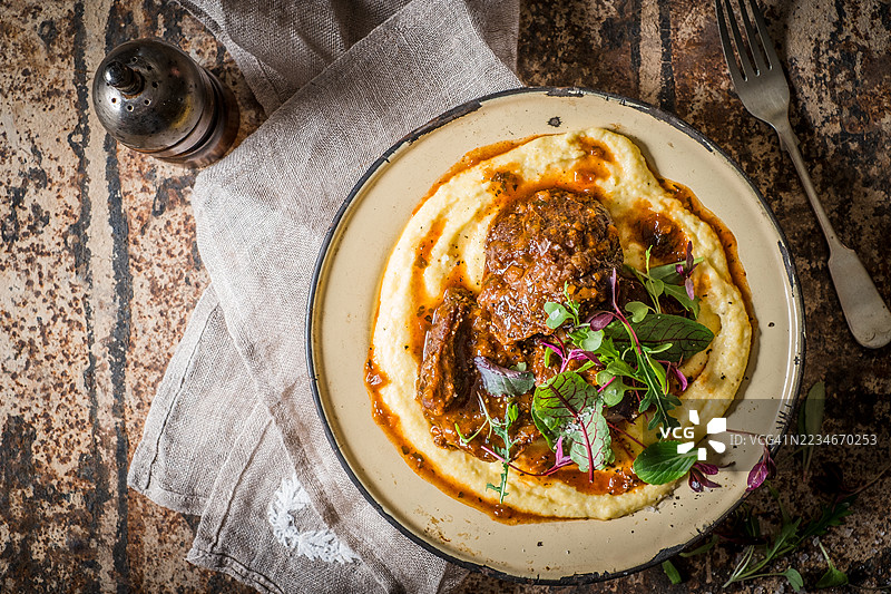 美味的舒适食品盘，配有酱汁和装饰性绿叶，摆放在乡村风格的桌子上图片素材