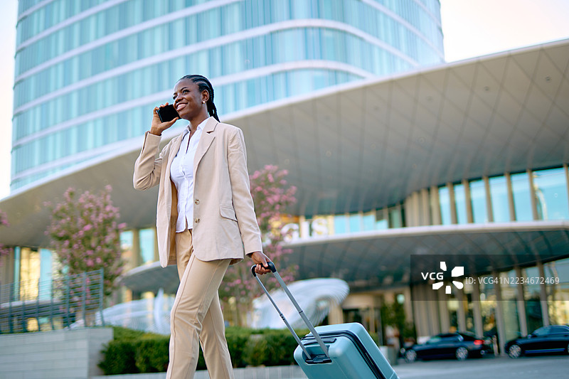 在现代建筑前走路并打电话的女商人图片素材