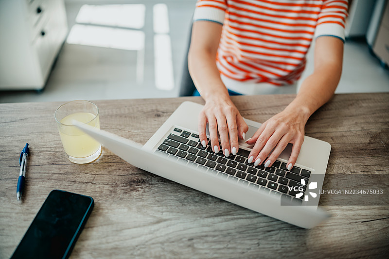 年轻的成年人在舒适的厨房桌子上使用笔记本电脑，度过一个高效的下午图片素材