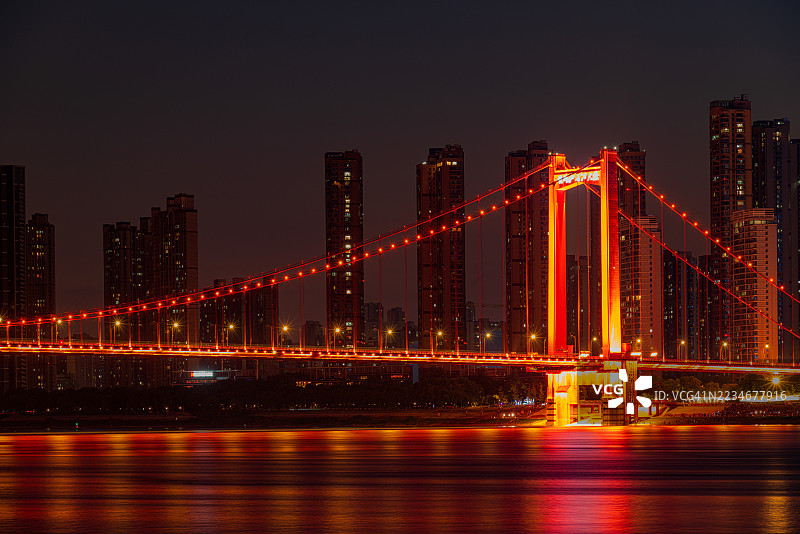 夜晚城市天际线下的红色灯光桥横跨河流，武汉，中国图片素材