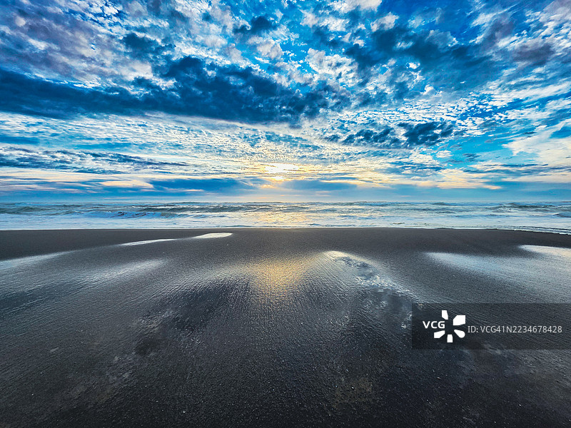 宁静的海滩在日出时分与戏剧性的云彩图片素材