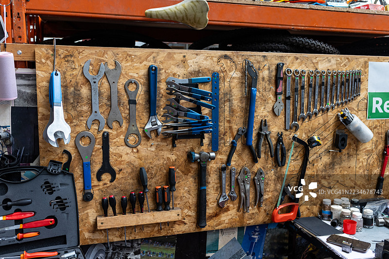 有序的自行车修理工具挂在刨花板墙上图片素材