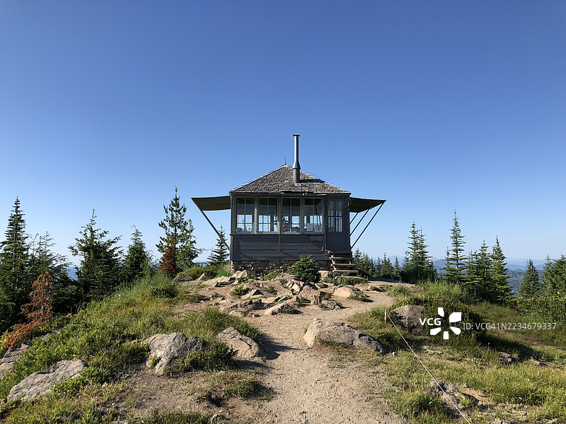 被松树环绕的山间小屋在晴朗的蓝天下图片素材