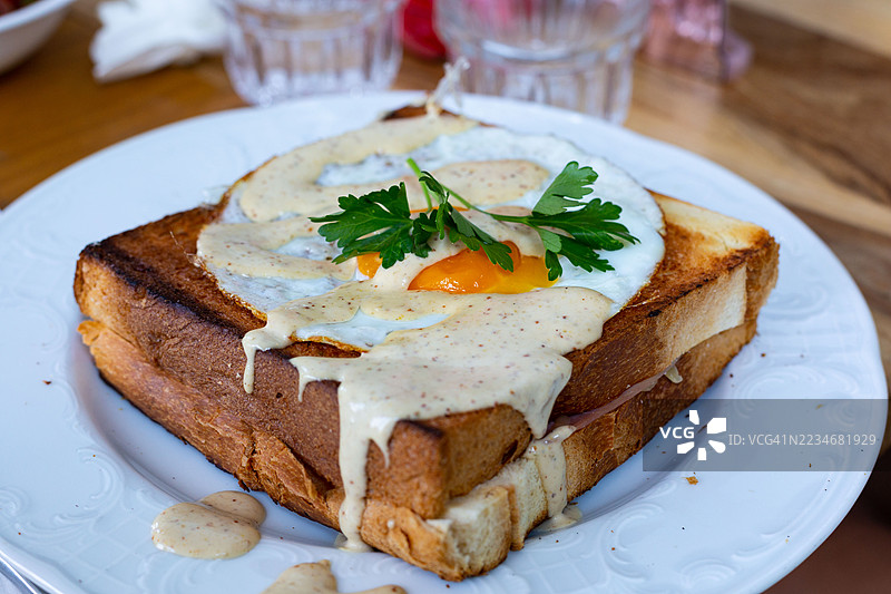 盘子里的可颂三明治，配有煎蛋和酱汁图片素材