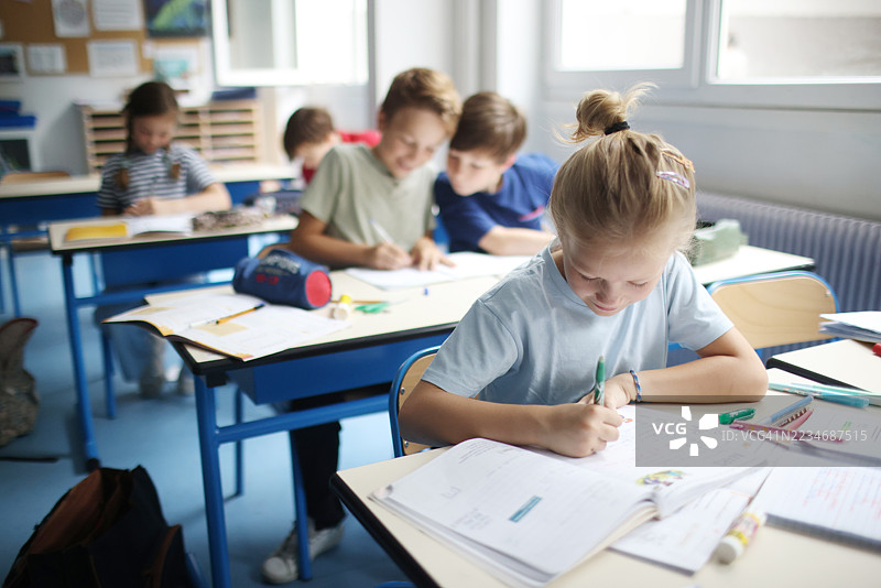 几个孩子在教室里写笔记本。图片素材