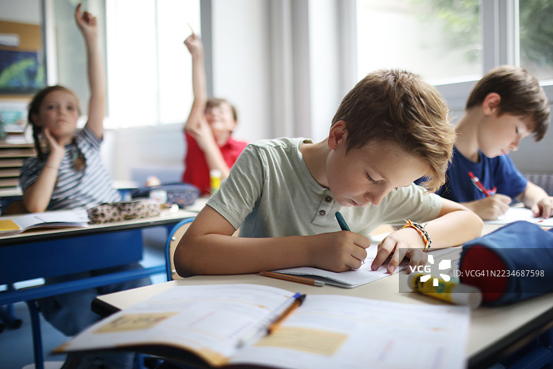几个孩子在教室里写笔记本。图片素材