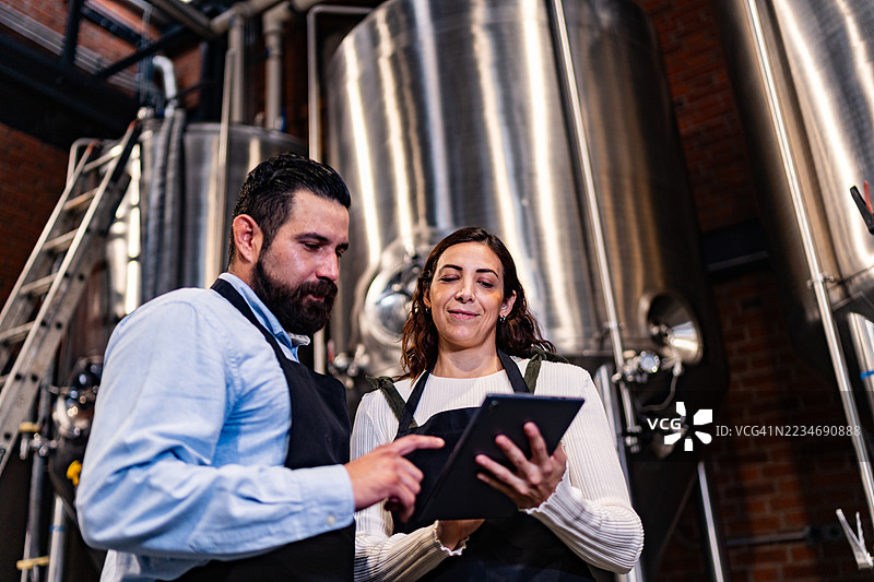 同事们在酿酒厂交谈并使用数字平板电脑图片素材