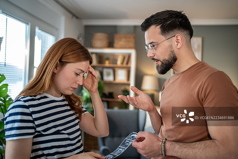 年轻情侣因意外怀孕争吵，手中拿着超声波图像图片素材