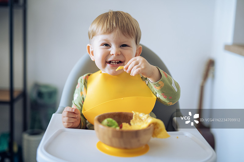 可爱男孩在家自己吃早餐。图片素材
