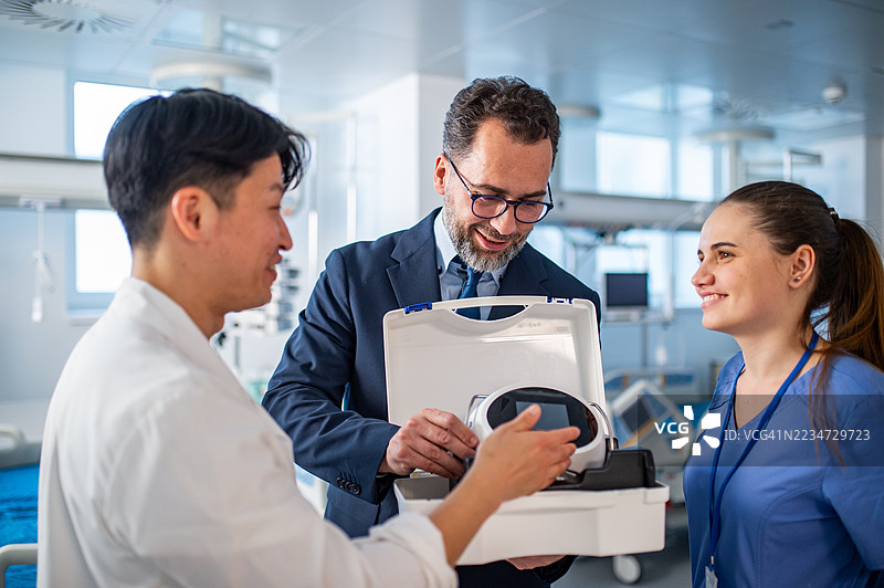 药品销售代表与医生交谈，展示新医疗技术。图片素材