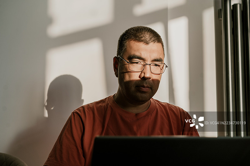 在自然光和阴影效果下工作的男子与笔记本电脑图片素材