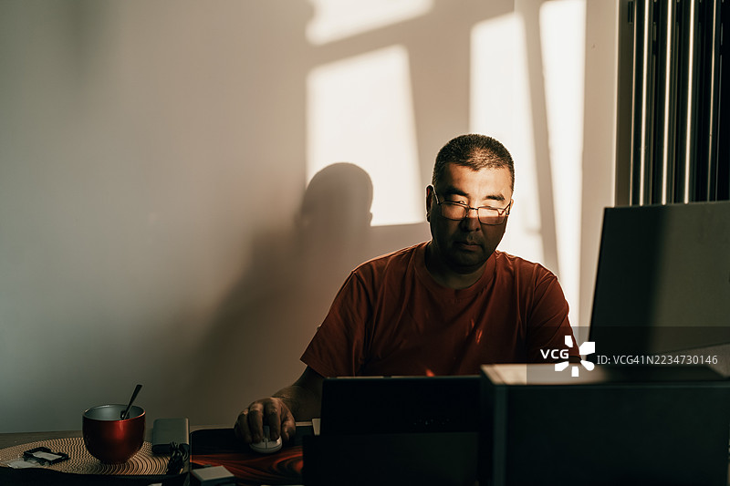 在阳光明媚的墙前工作的人正在使用电脑图片素材