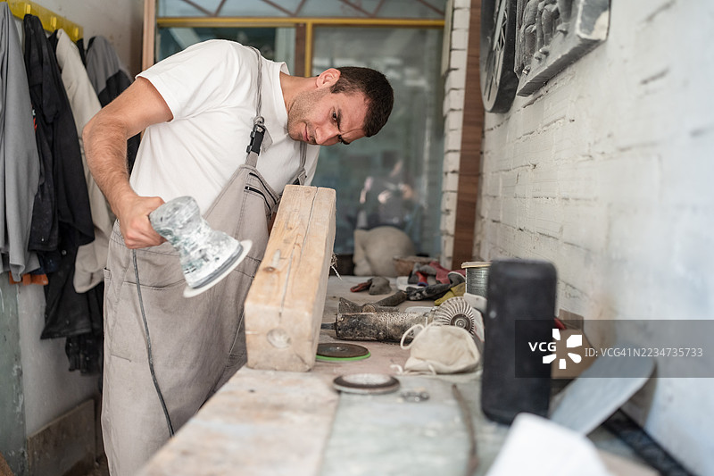 木匠在工作坊中使用电动砂光机专注于精细木工。图片素材