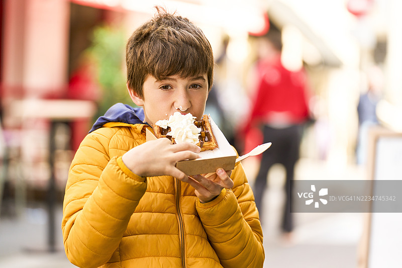 男孩在户外享用奶油华夫饼图片素材