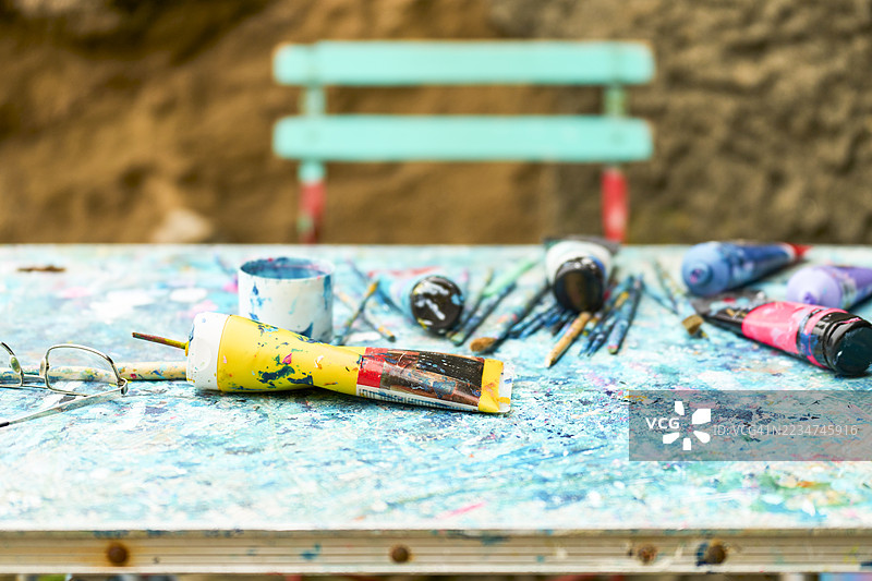 色彩缤纷的颜料管和画笔的绘画桌，展现出创意的混乱图片素材
