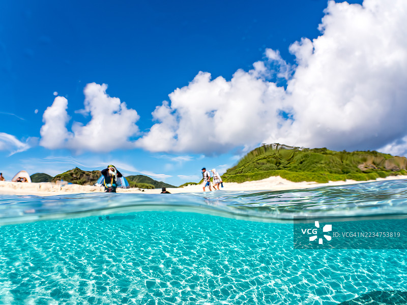 可以看到阳伞、船只，甚至是独特于冲绳的双体船Sabani。拍摄了美丽白沙滩的一半。还有一群热带鱼。美丽的珊瑚礁和游泳的人们。外岛、座间味岛、慶良間群岛。图片素材