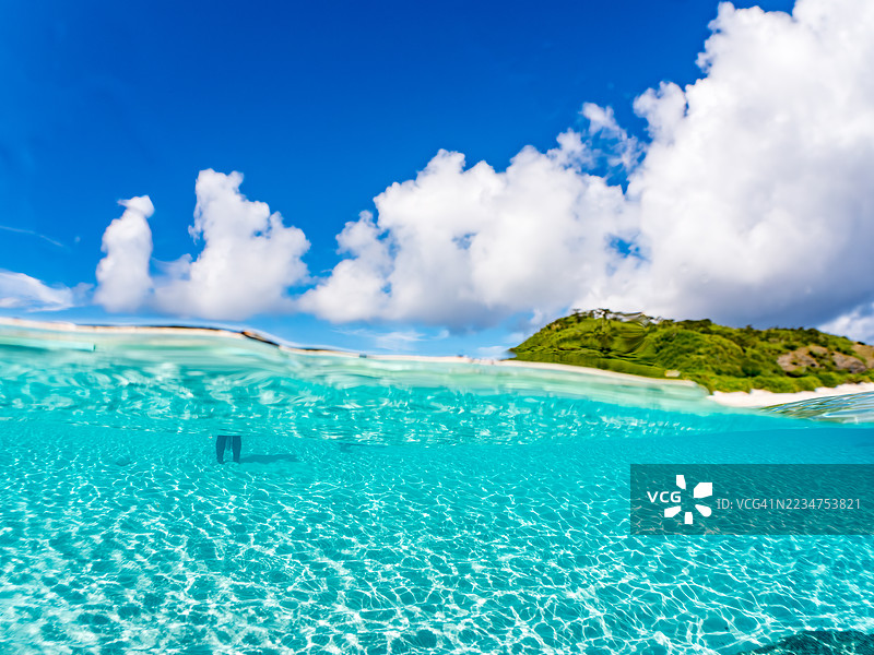 可以看到阳伞、船只，甚至是独特于冲绳的双体船Sabani。拍摄了美丽的白沙滩的一半。还有一群热带鱼。美丽的珊瑚礁和游泳的人们。外岛，座间味岛，慶良間群岛。图片素材